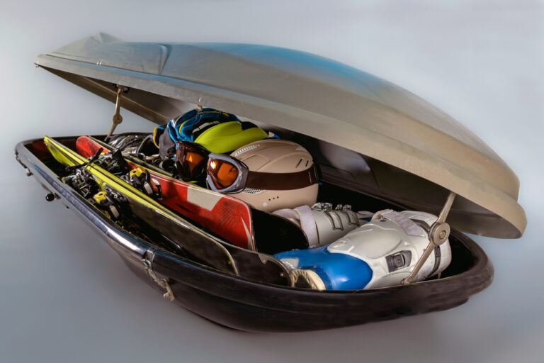 Otvorený strešný box plný športového vybavenia vrátane lyží, lyžiarok, prilieb a okuliarov.